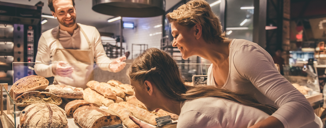 Parents and children look at a bread display with stylish price card designs